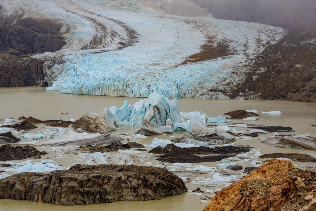marked retreat of one of the glaciers of Chilean Patagonia, surrounded by dark moraines and a murky glacial lake
