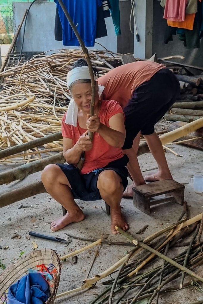 Elderly woman preparing cinnamon sticks with handmade tools in a Vietnamese village