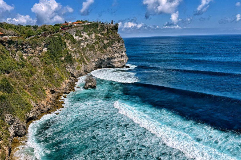 View of the cliffs of Uluwatu in Bali with waves against the rocky coastline.