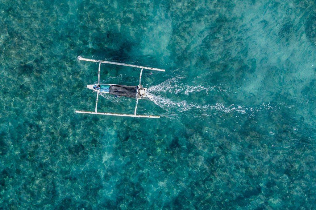 aerial view of an outrigger boat sailing on a turquoise sea