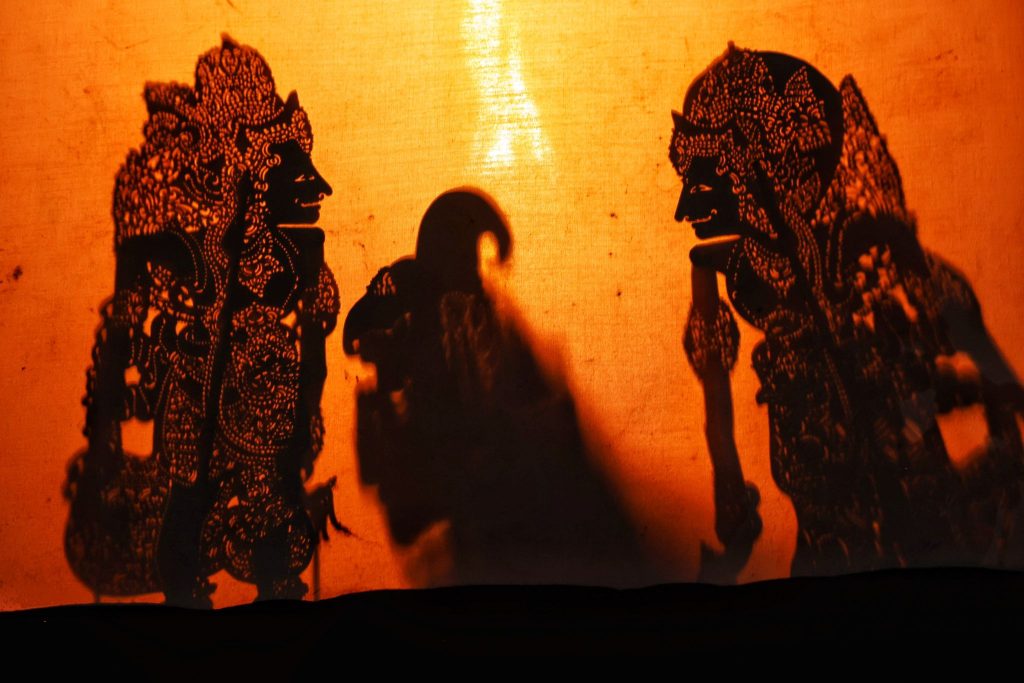 Silhouettes of Wayang Kulit puppets projected onto a screen in Bali during a traditional performance.