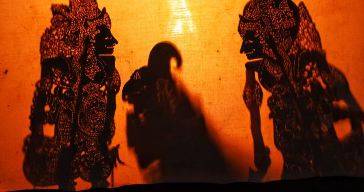 Silhouettes of Wayang Kulit puppets projected onto a screen in Bali during a traditional performance.