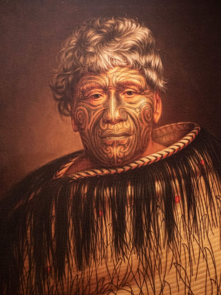 Portrait of a Maori man with Ta Moko facial features and traditional clothing made of fibers