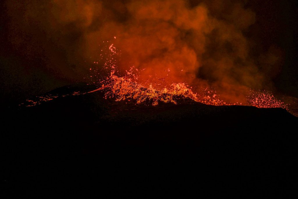 Éruption volcanique de nuit avec projections de lave et fumée