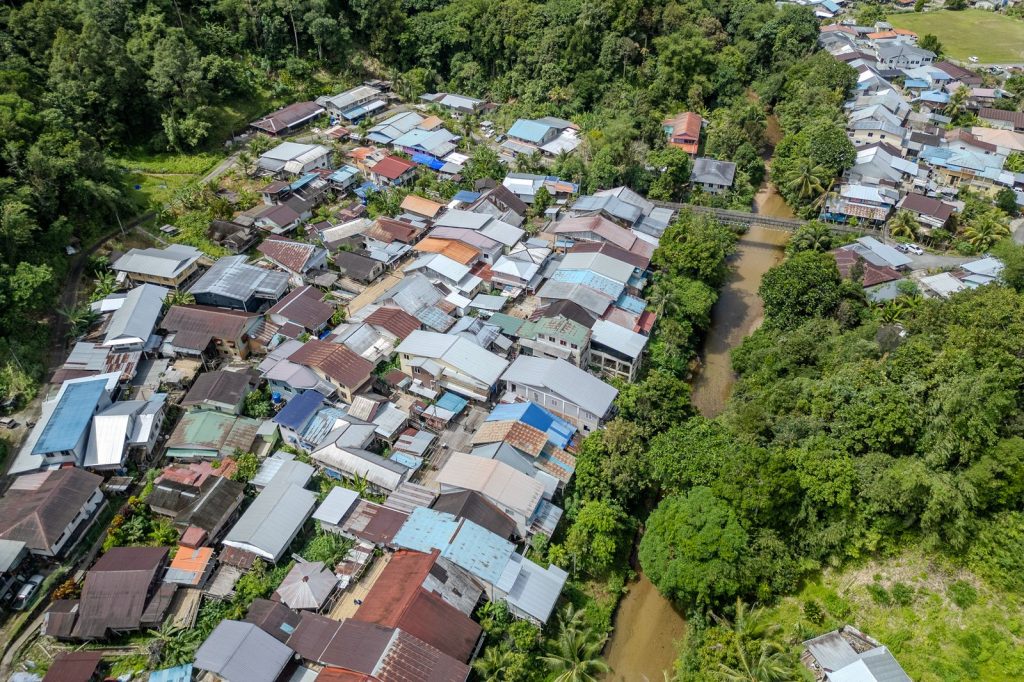 Vue aérienne d'un village entouré de forêt traversé par une rivière.