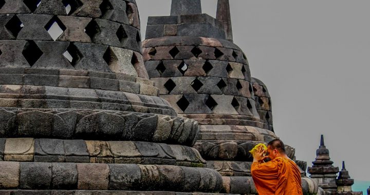 Moine bouddhiste assis devant les stupas du temple de Borobudur en Indonésie.