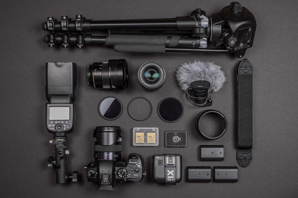 Équipement de tournage documentaire avec caméra, objectifs et accessoires sur fond noir. (image libre de droits par alflucio)