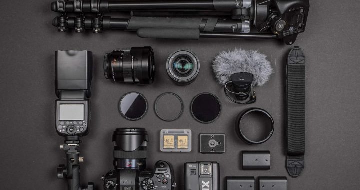 Équipement de tournage documentaire avec caméra, objectifs et accessoires sur fond noir. (image libre de droits par alflucio)