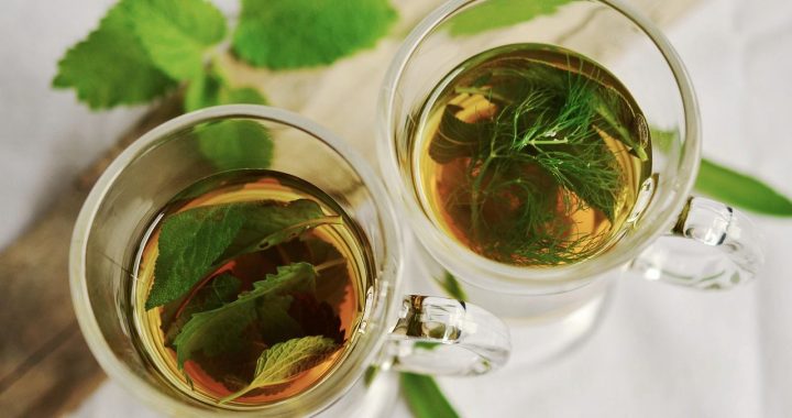 Cups of infused tea with leaves and aromatic herbs.