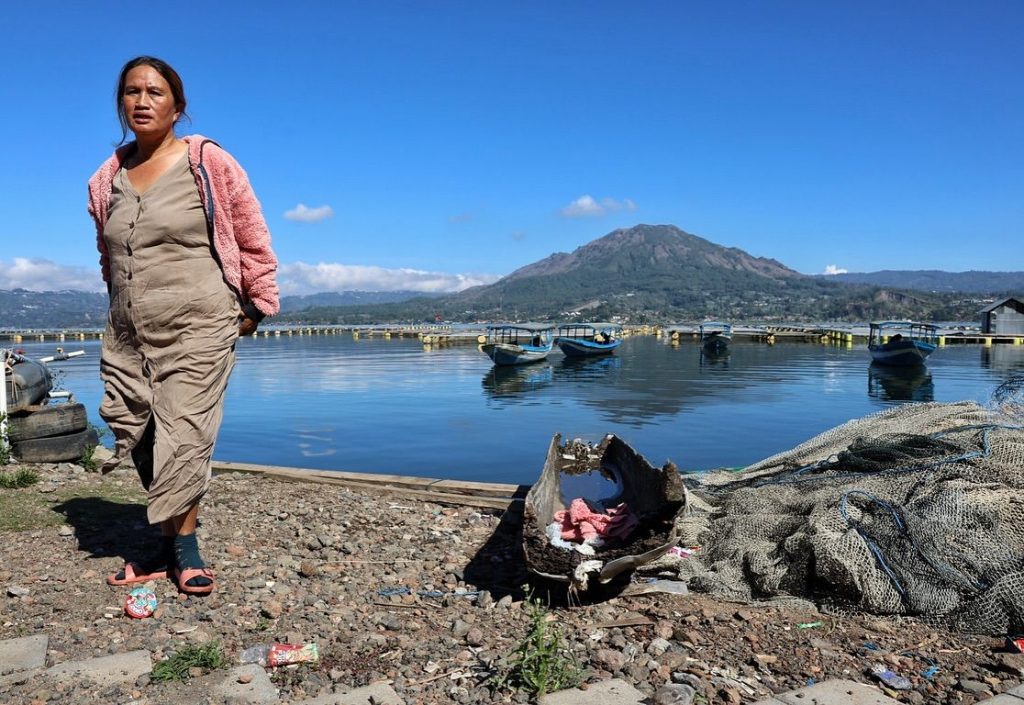 Habitante marchant près d’un lac volcanique avec un volcan en arrière-plan