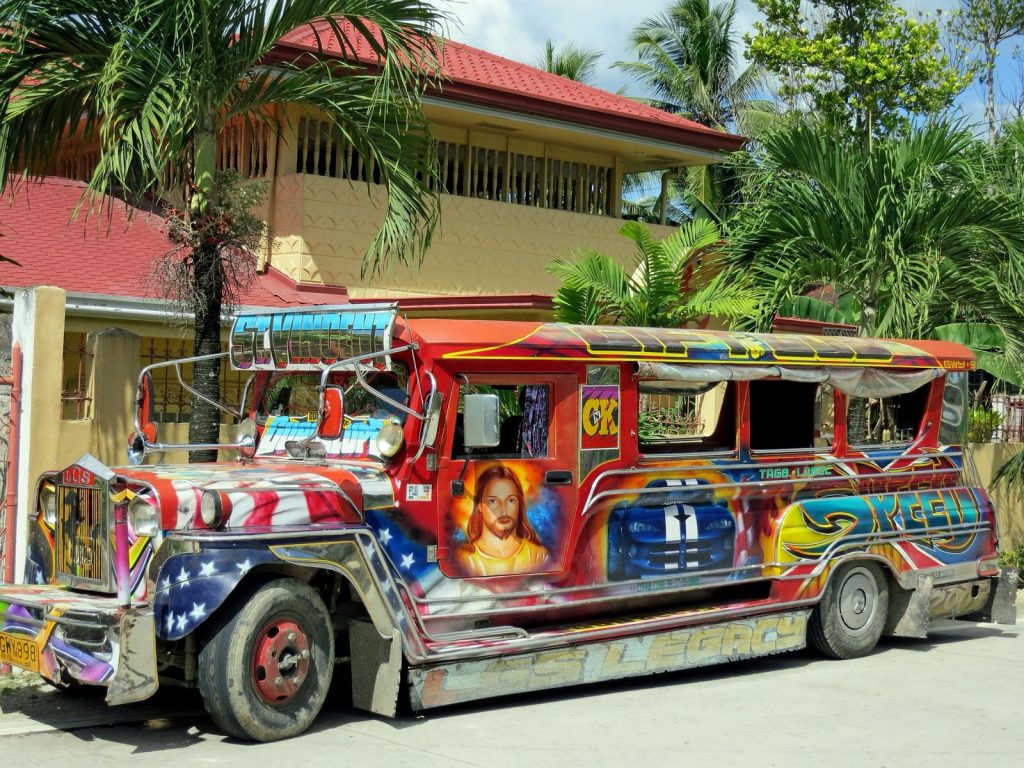 Jeepney coloré stationné devant une maison tropicale aux Philippines.