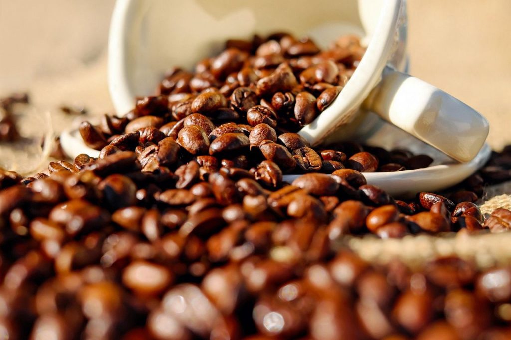 Grains de café torréfiés renversés depuis une tasse en céramique.