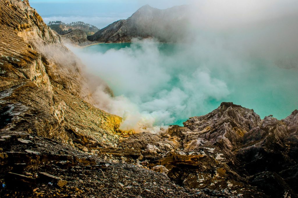 The turquoise acidic lake of Ijen Crater surrounded by volcanic fumaroles in East Java.