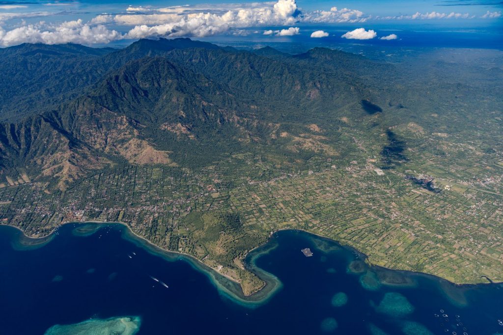 Aerial view of Mount Agung, Bali's agricultural plains and coastline shaped by volcanic activity.