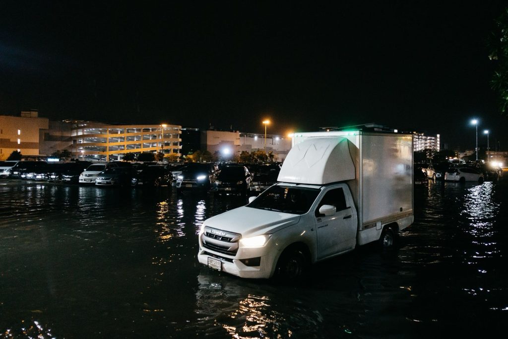 Vehicles driving through floodwater in a parking area in Bangkok, Thailand