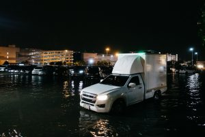 Vehicles driving through floodwater in a parking area in Bangkok, Thailand