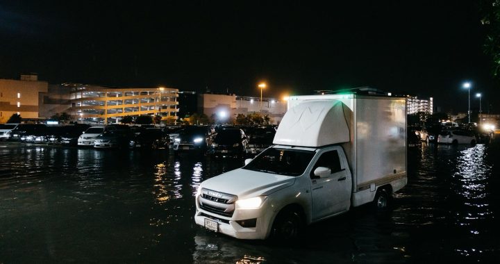 Vehicles driving through floodwater in a parking area in Bangkok, Thailand