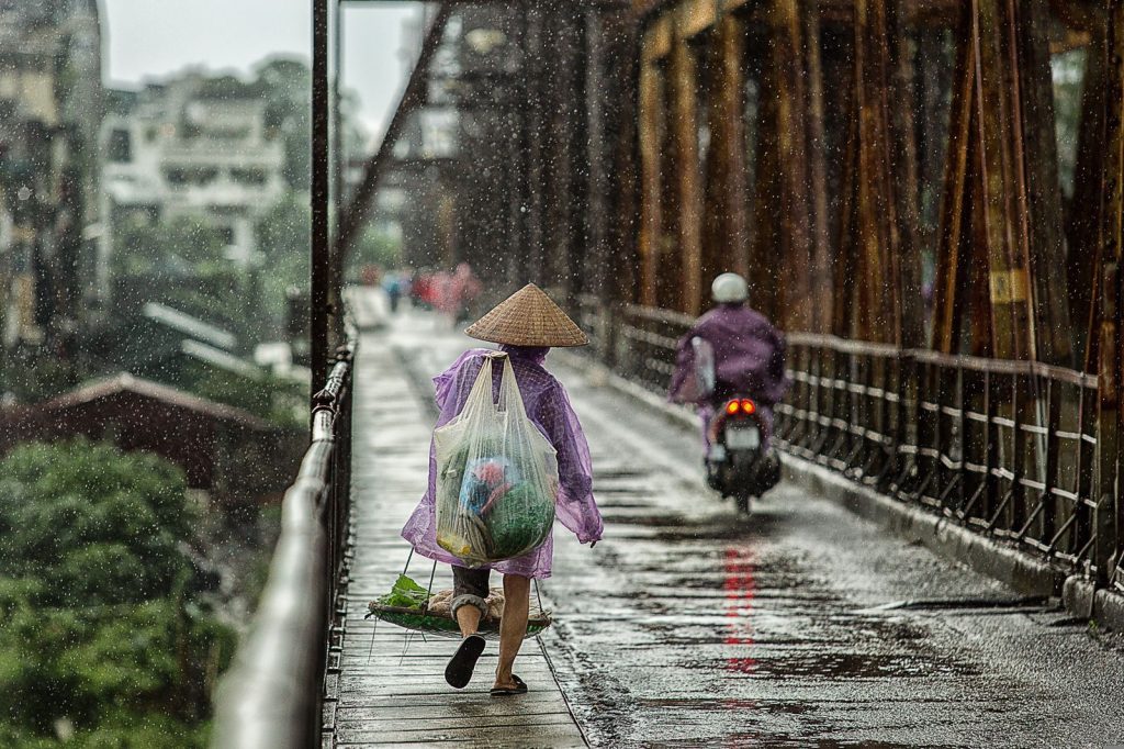 Person walking through heavy rain on an urban street in Southeast Asia
