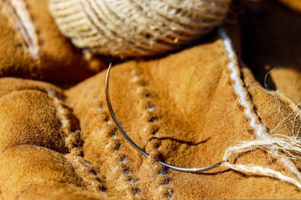 Gros plan sur une aiguille et un fil utilisés pour la couture artisanale du cuir.