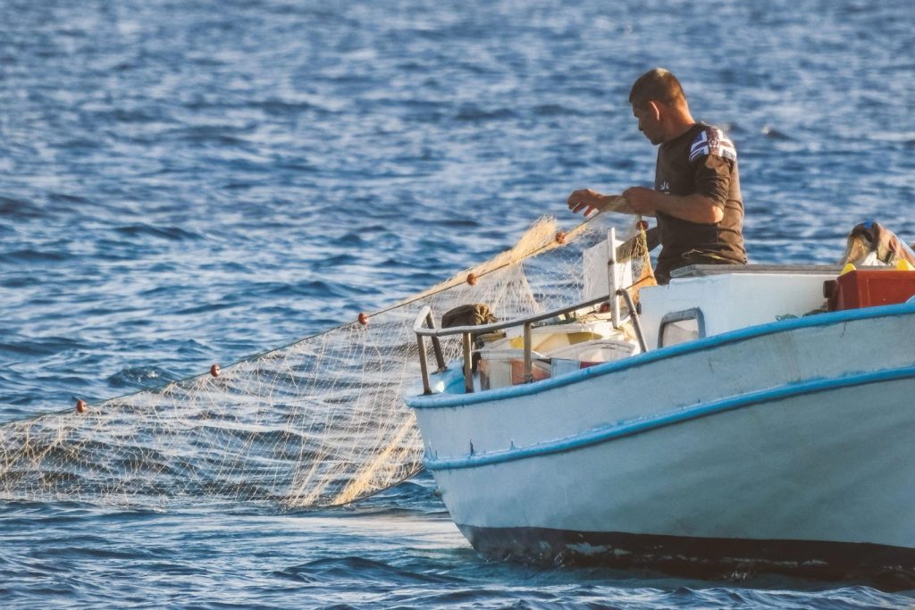 A fisherman handling a gillnet aboard a small fishing boat.