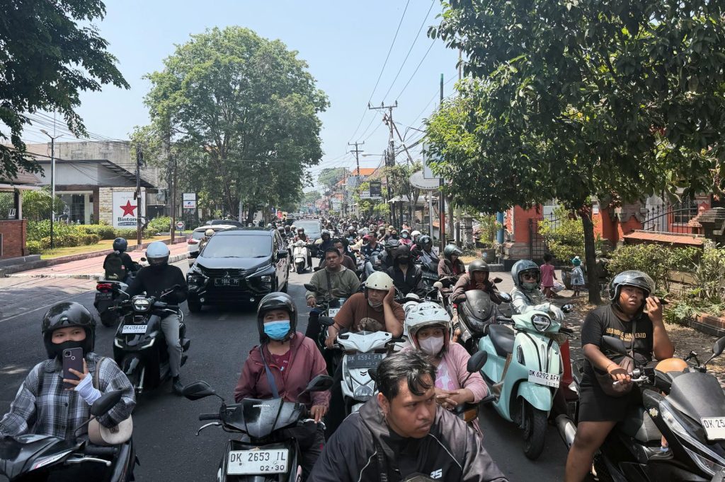 Heavy motorcycle and car traffic fills a road in Bali as fuel shortages disrupt daily transportation across the island.
