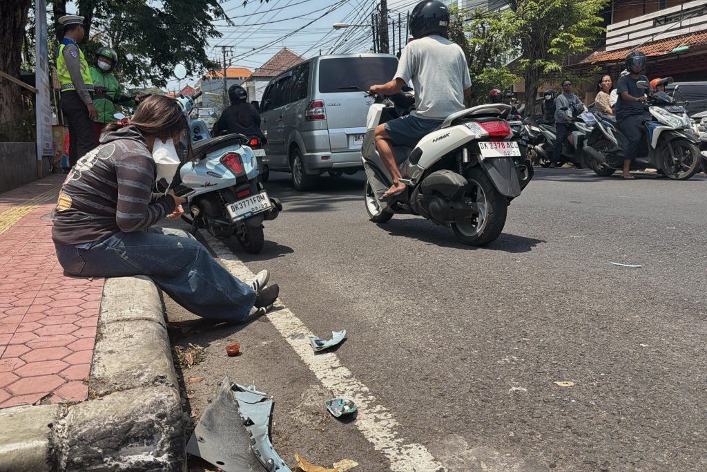 Police officers and motorists near a damaged scooter following a road accident amid heavy traffic in Bali.